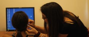 A female researcher connecting an experiment's participant with an EEG.