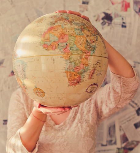 Person holding a globe infrond of their face.